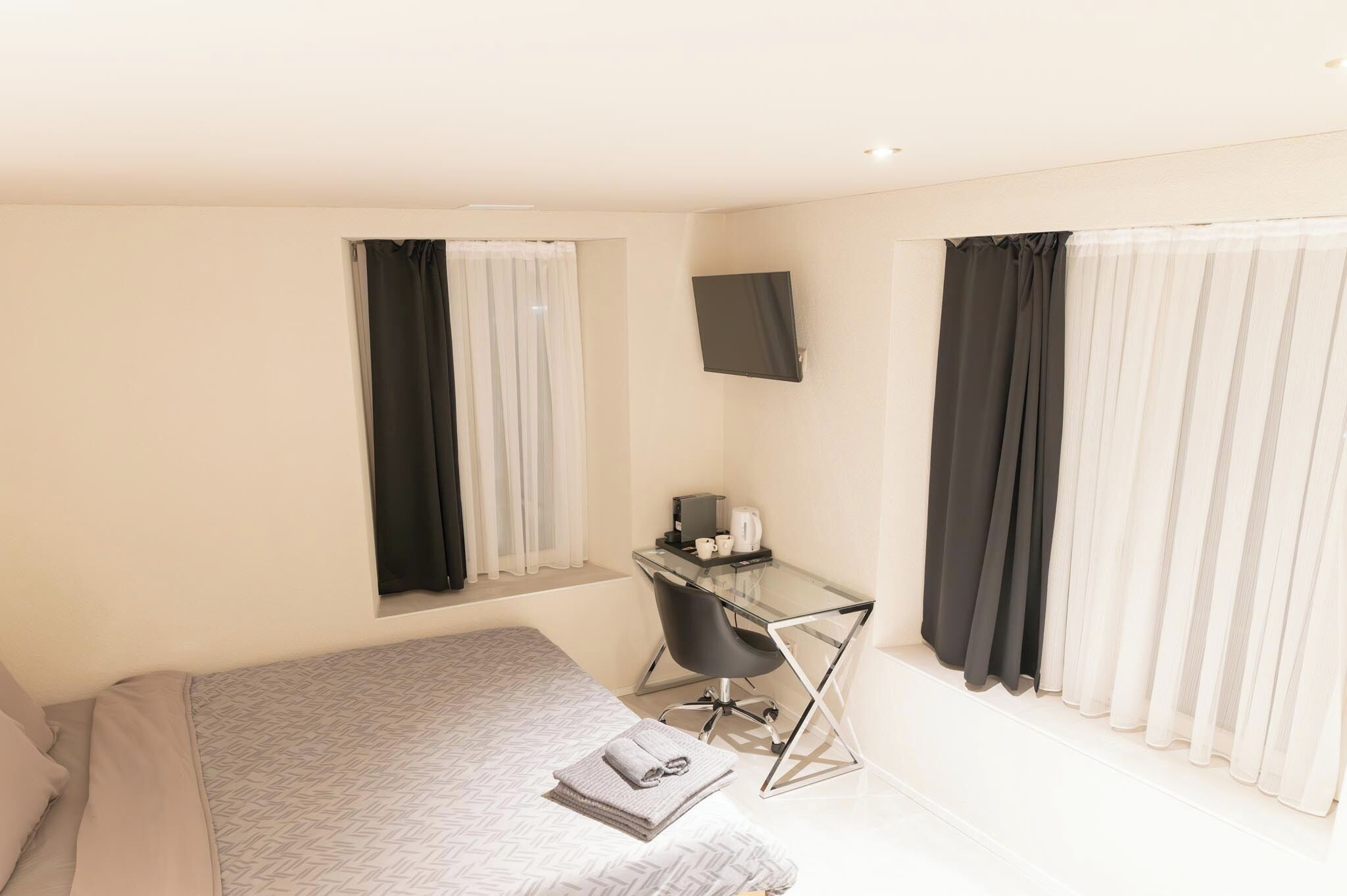 A hotel room with a bed, a desk, and a TV.