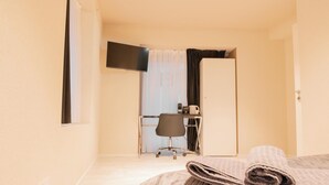 Una habitación de hotel con una cama, un escritorio, una silla y un televisor montado en la pared.