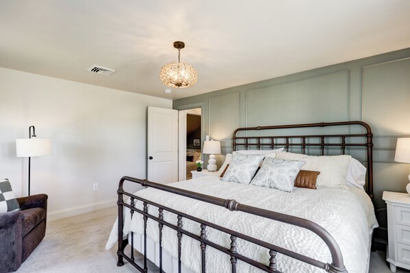 A bedroom with a bed, bedside tables, a lamp, a chair, and a hanging light fixture. - Spacious 5bdrm house with AC and WiFi /Family Friendly/Fire Pit /HOT TUB (Gordonville)