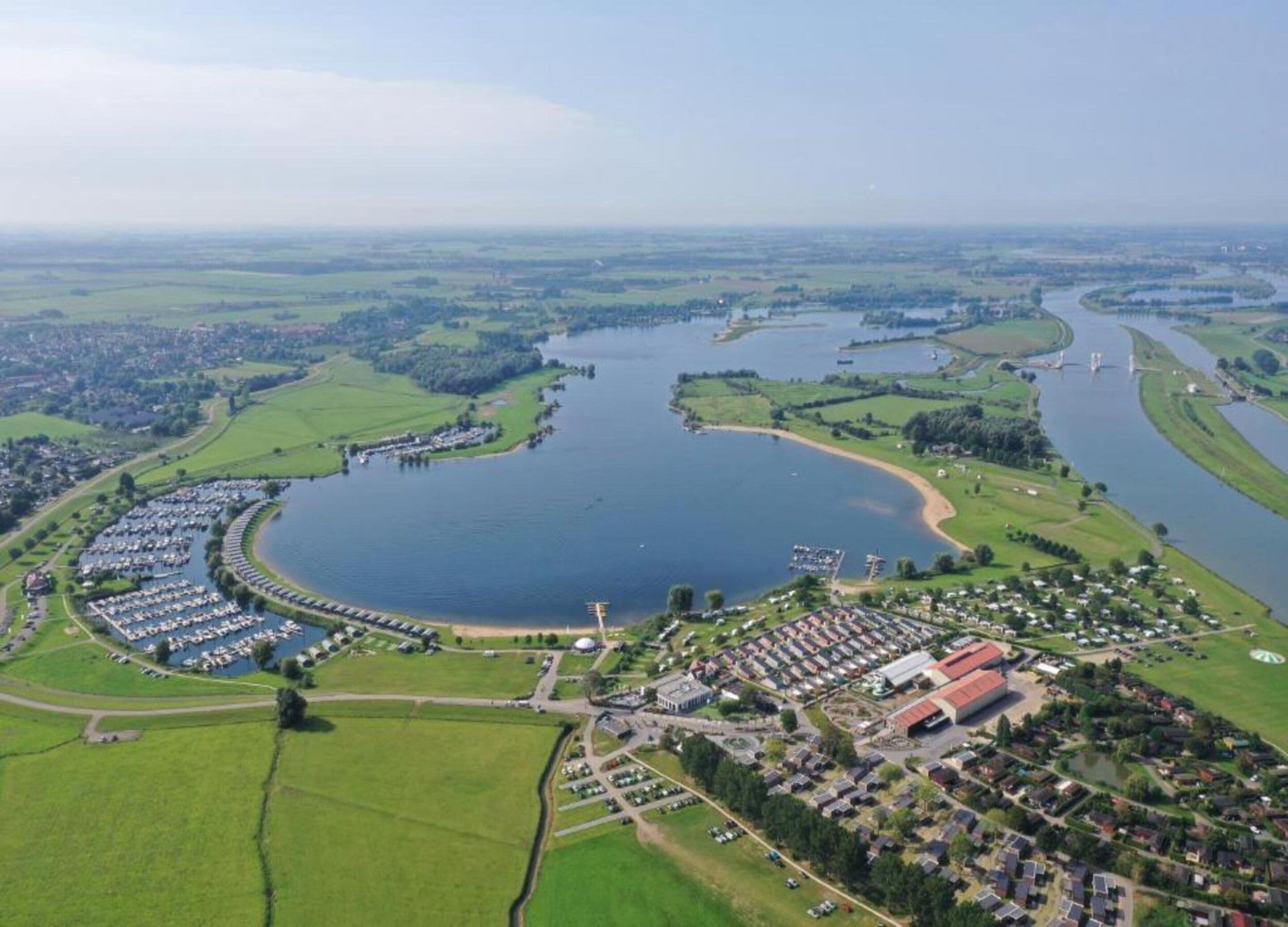An aerial view of a lakeside residential area with a marina, houses, and a large body of water.
