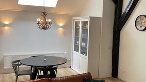 A dining area with a round table, chairs, a chandelier, and a cabinet with glass doors. - Apartment in Wageningen Near Rhine River (Elst)