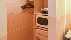 A compact room with a kitchenette, a microwave, a small oven, and a hanging clothes rack. - Mid-Century Themed Hotel Room in Fayetteville, AR - The Clementine on College #5 (Fayetteville)