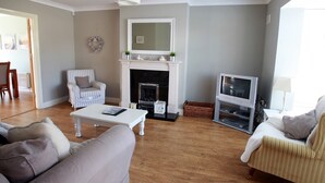 A living room with a fireplace, a television, and two sofas. - Glen Ard Holiday Home no. 1 (Dunmore East)
