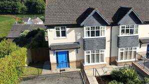 A two-story house with a grey tiled roof, a blue door, and a brick facade. - Glen Ard Holiday Home no. 1 (Dunmore East)
