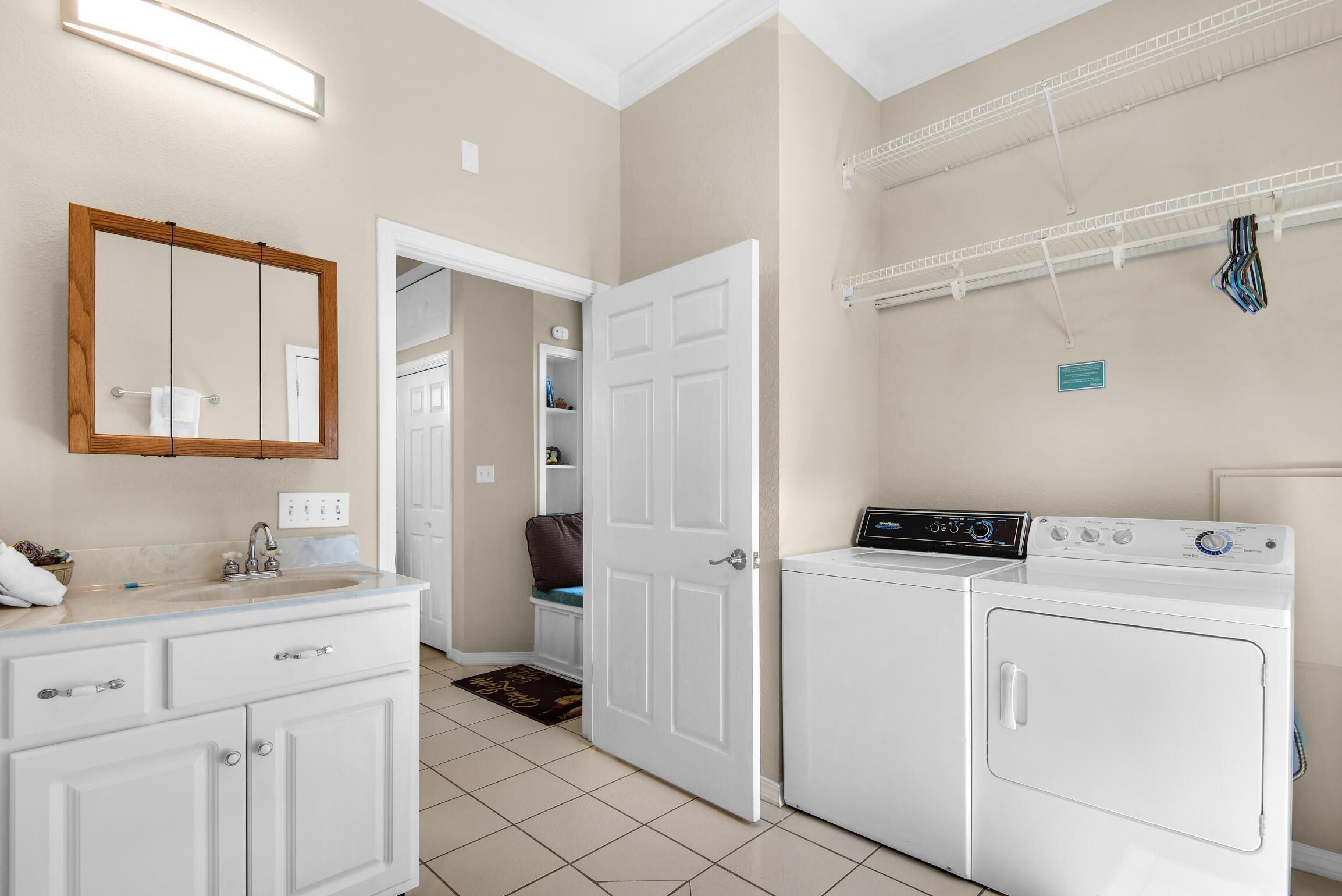 A laundry room with a washing machine, dryer, and a mirror above the sink.