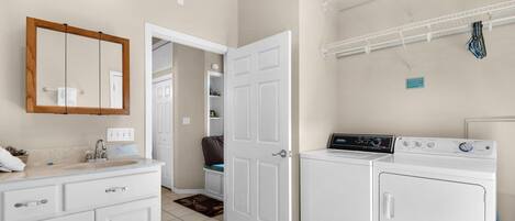 A laundry room with a washing machine, dryer, and a mirror above the sink.