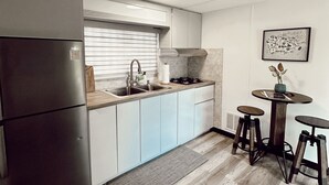Eine kleine Küche mit Kühlschrank, Spüle und einer Essecke mit Hockern.