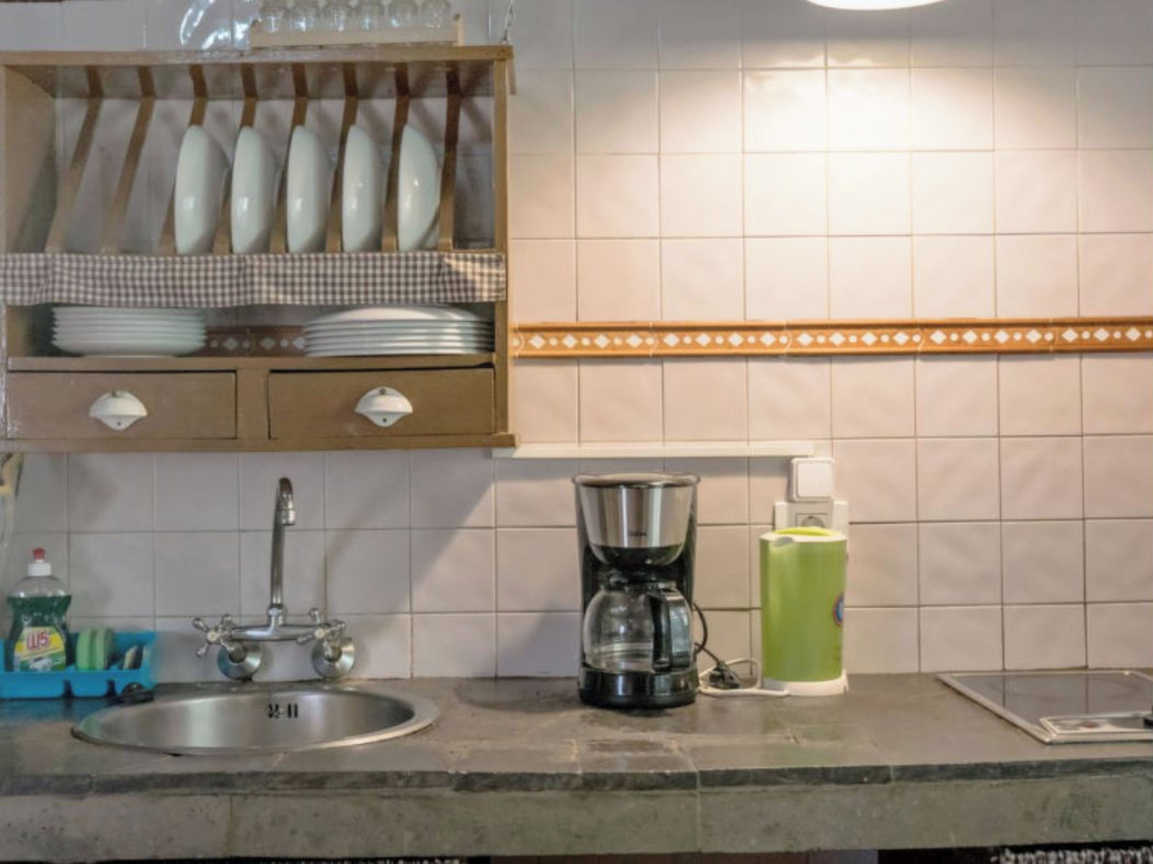 A kitchen with a sink, a coffee maker, and a dish rack.