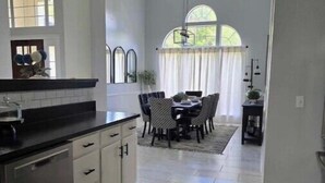 A spacious kitchen with a dining area, featuring a large island, modern appliances, and a view of the outdoors. - The Dreamy Dwelling (Pooler)