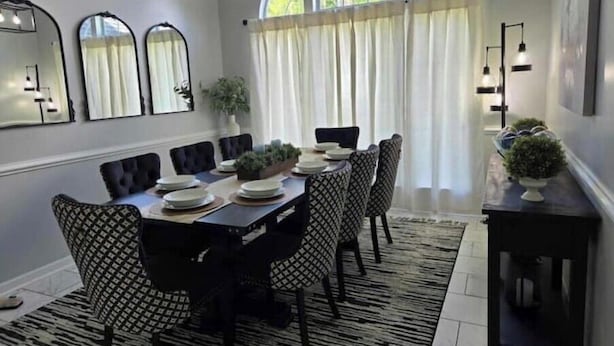 A dining room with a rectangular table set for six, surrounded by patterned chairs, a large mirror, and a chandelier. - The Dreamy Dwelling (Pooler)