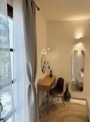 Cozy retreat with a single bed, desk, and mirror, offering a peaceful atmosphere.