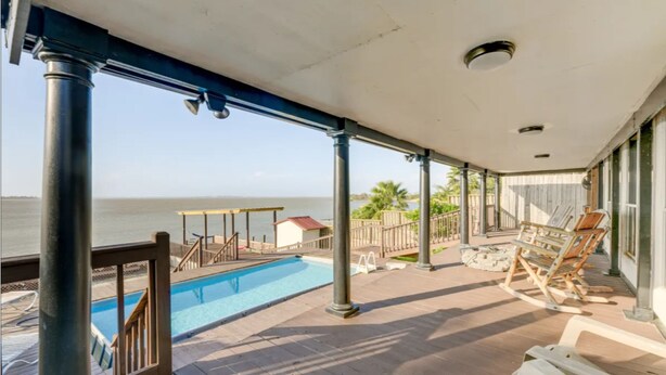 Ein überdachter Außenbereich mit Pool, Holzterrasse und Liegestühlen.