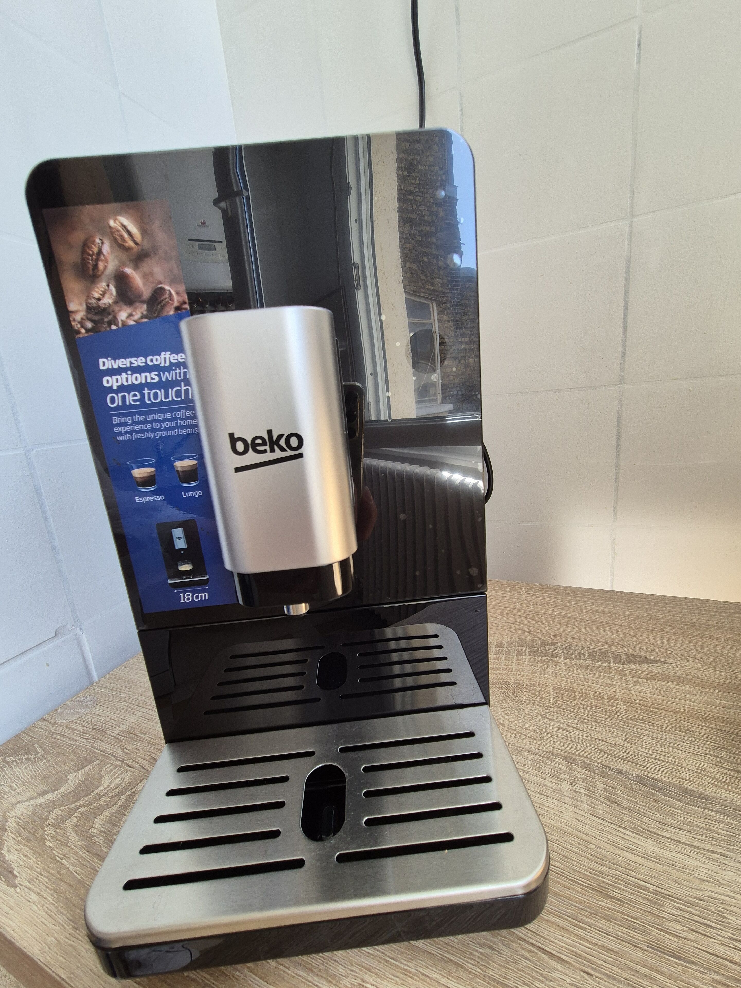 A Beko coffee machine with a digital display, placed on a wooden surface.