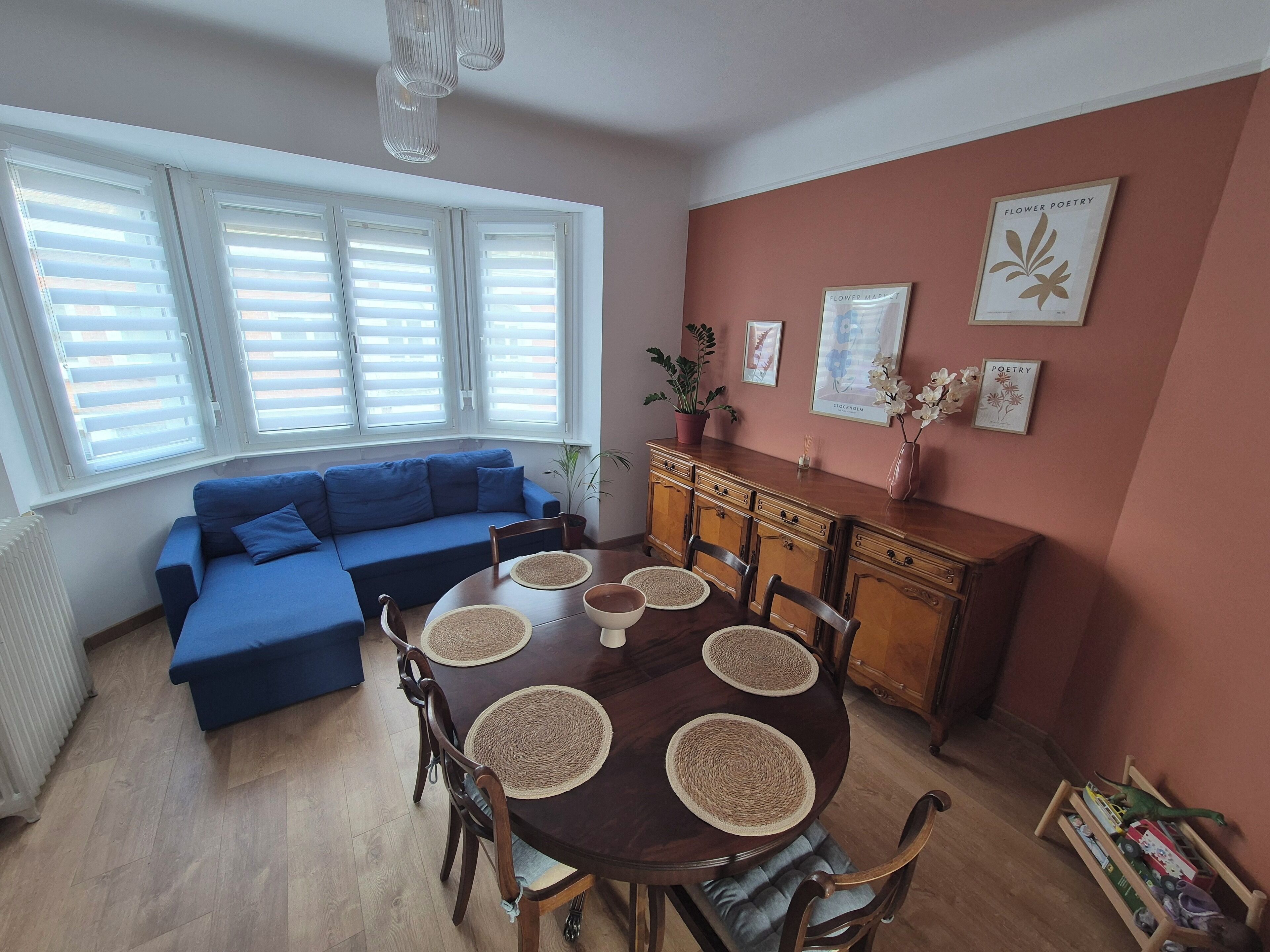 Un coin repas comprenant une table ronde, des chaises, un canapé bleu et un meuble en bois.