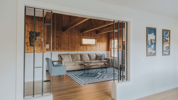 A modern living room with a wooden ceiling, a sofa, a coffee table, and a blue rug.