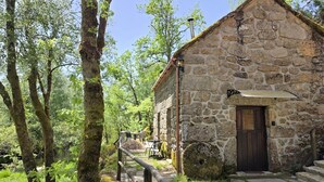 Un bâtiment en pierre avec une porte en bois, un petit porche et un chemin en pierre menant à l’entrée.