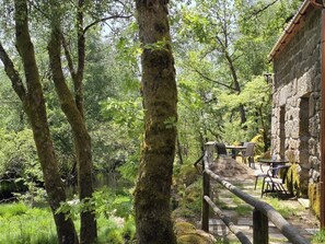 Un bâtiment rustique en pierre, doté d’une terrasse en bois et d’un espace salon extérieur.