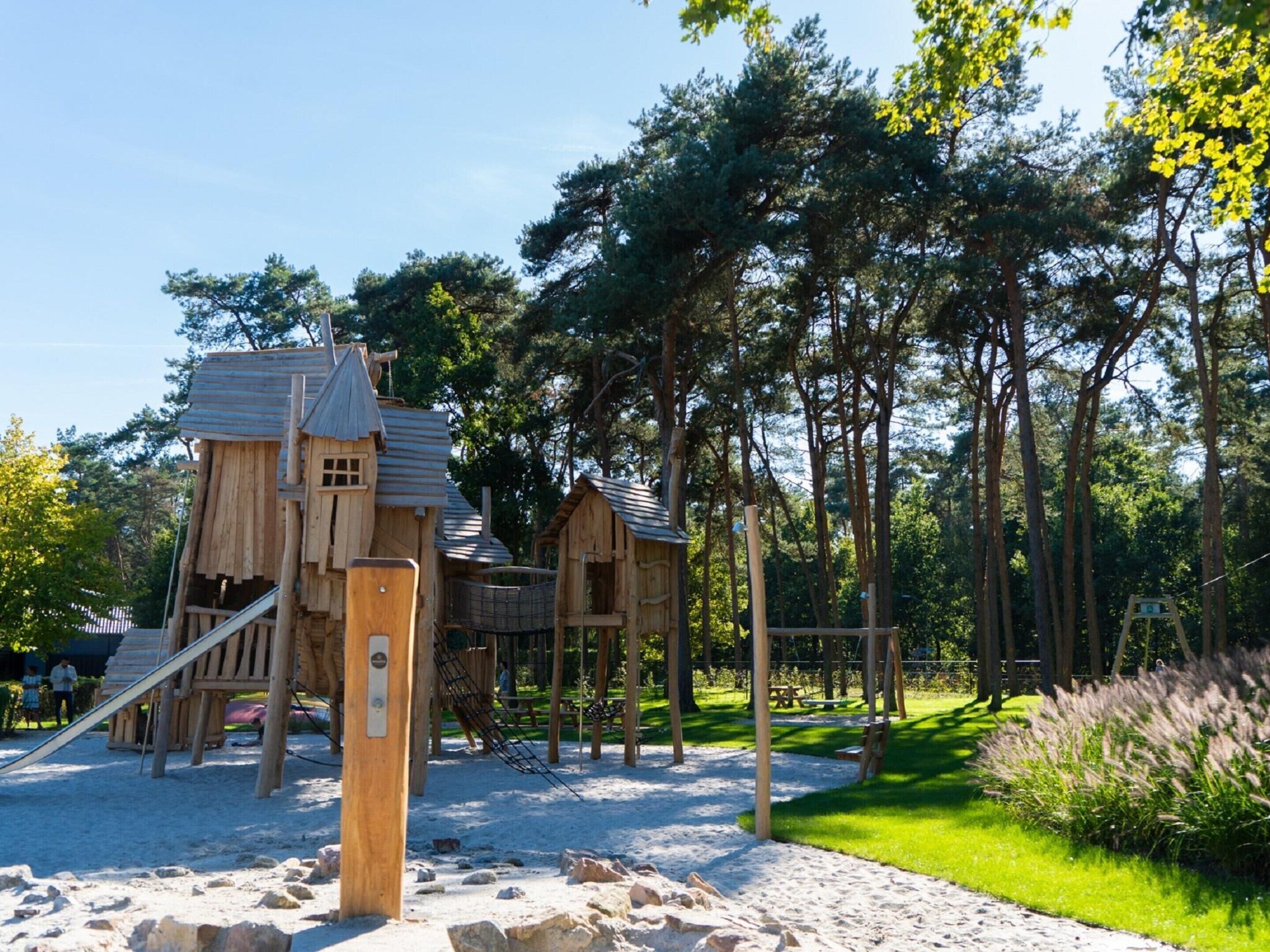 A playground with wooden play structures and a sandy ground.