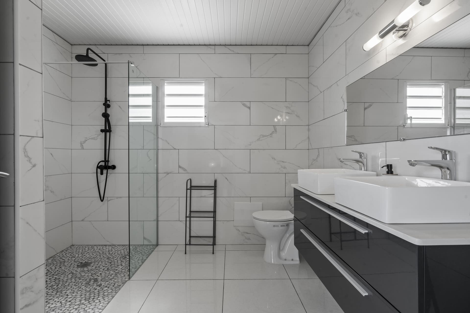 A modern bathroom with a walk-in shower, a toilet, and a double sink vanity.
