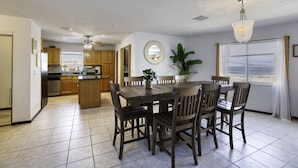 A spacious kitchen with wooden cabinets, a central island, and a dining area with a table and chairs. - 99 Problems & the Beach Ain`t 1 (Daytona Beach)