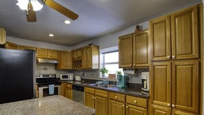 A kitchen with granite countertops, wooden cabinets, a black refrigerator, a microwave, a stove, and a dishwasher. - 99 Problems & the Beach Ain`t 1 (Daytona Beach)