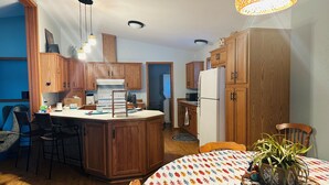 Una cocina con armarios de madera, una isla central y una mesa de comedor con mantel estampado de hojas.