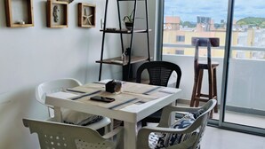 Uma sala de jantar moderna com uma mesa branca, cadeiras pretas e uma estante de metal preta.