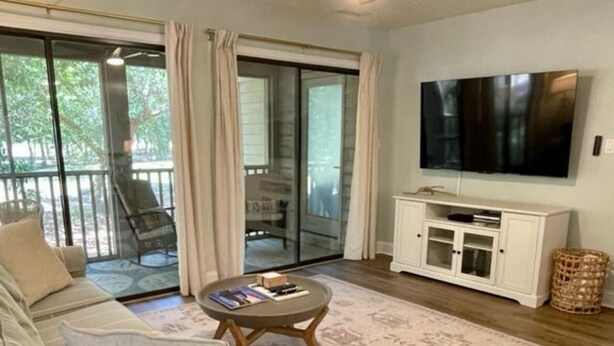 Ein Wohnzimmer mit einer Couch, einem Couchtisch, einem Fernseher und einem Deckenventilator.