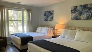 Ein Hotelzimmer mit zwei Betten, einem Sessel und Kunstwerken an den Wänden.