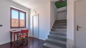 A room with a desk, a chair, a staircase, and a door.