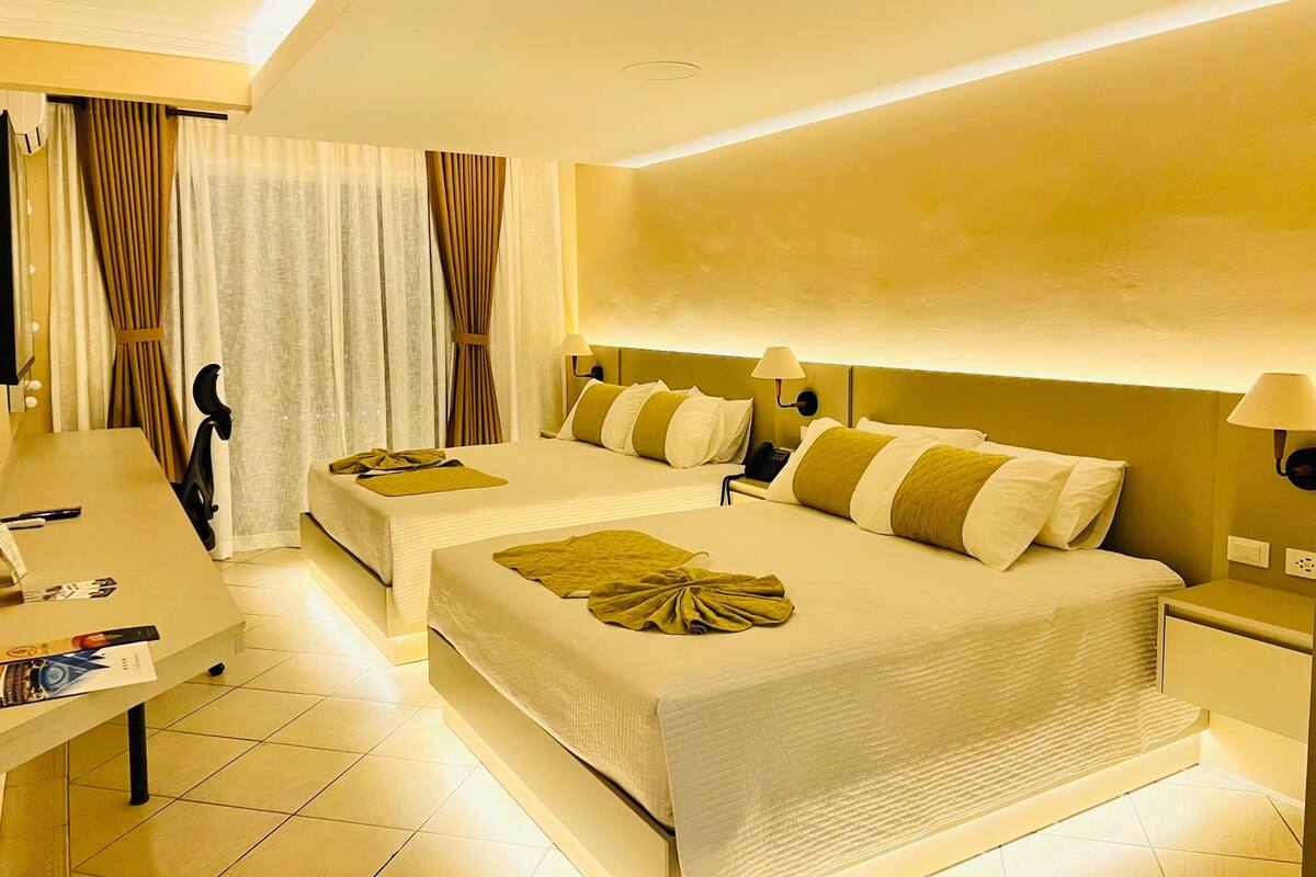 A hotel room with two beds, a desk, and a chair.