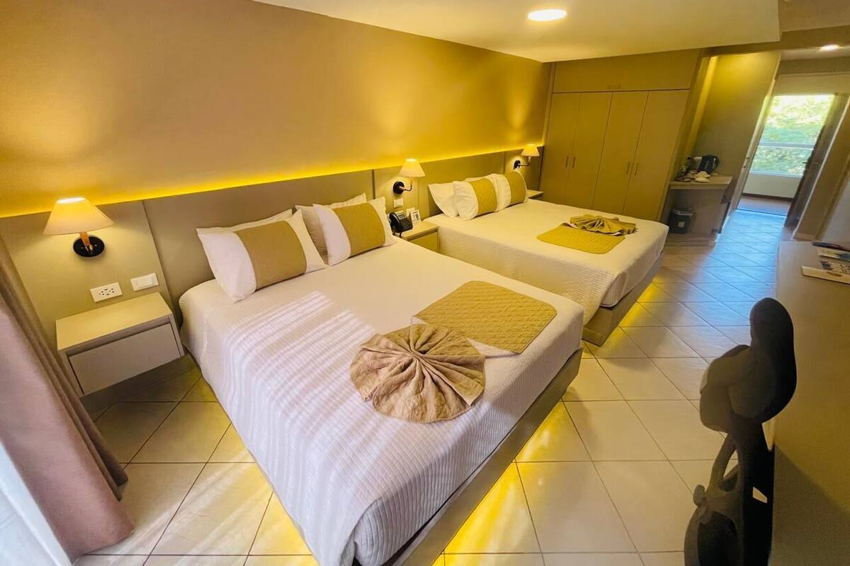 A hotel room with two beds, a desk, and a chair.