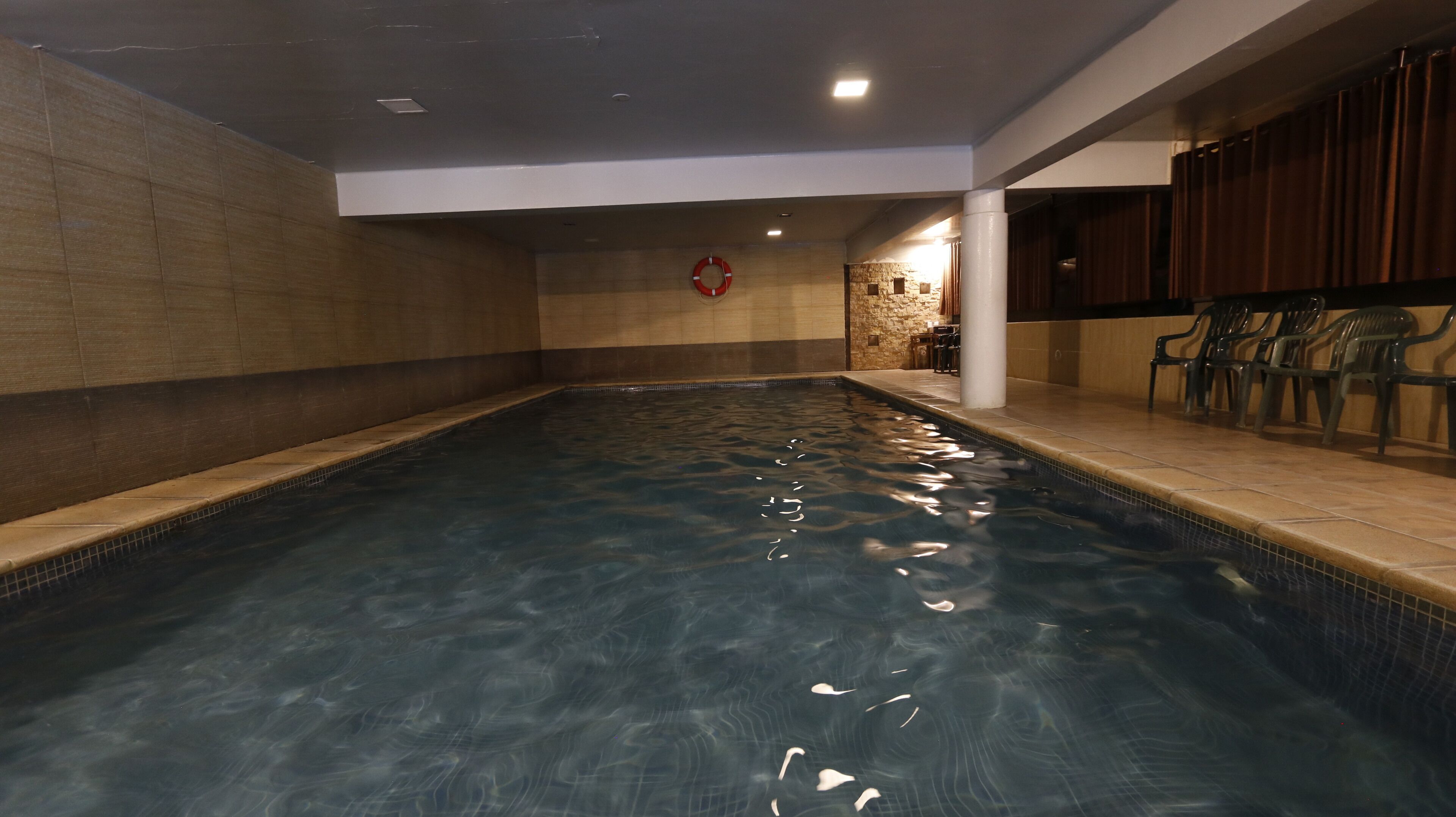 Una piscina interior con agua cristalina, paredes enlosadas y un flotador en la pared.