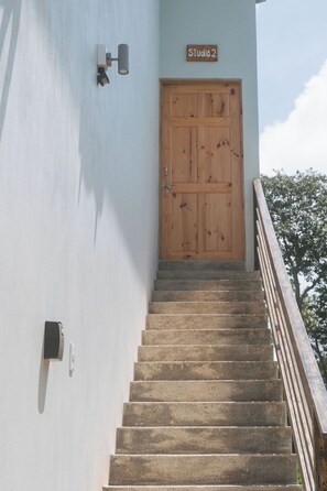 A staircase leading to a wooden door labeled "Studio 2" with a light fixture on the wall. - Cedrela Beach Villas (Bahía Ballena)