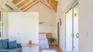 A modern room with a high wooden ceiling, a bed, a blue sofa, and a small table with a mat.