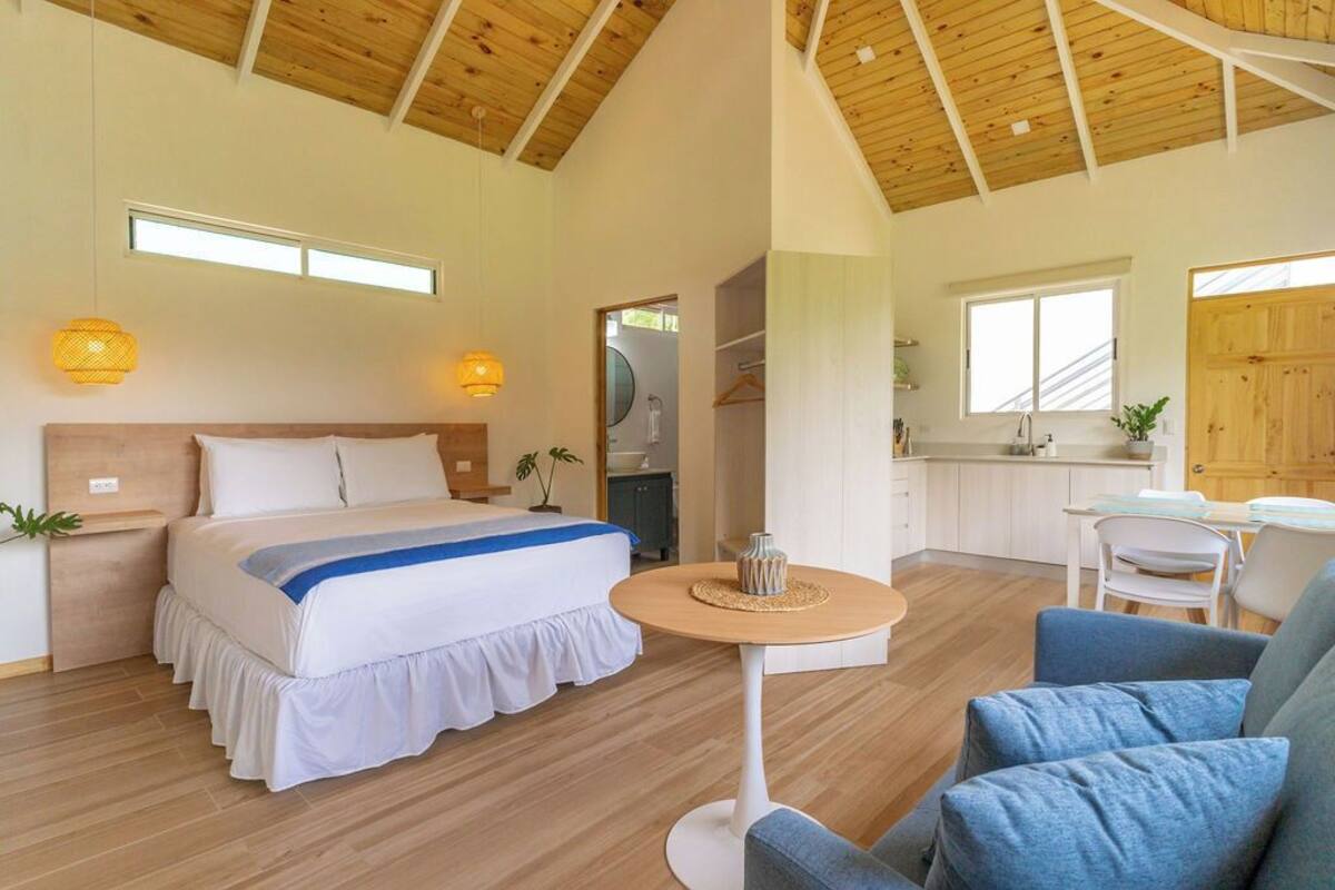 A spacious bedroom with a large bed, a round table, and a seating area.