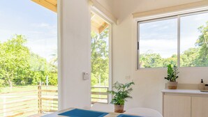 A modern kitchen with white cabinetry, a wooden ceiling, and large windows offering a view of the outdoors.