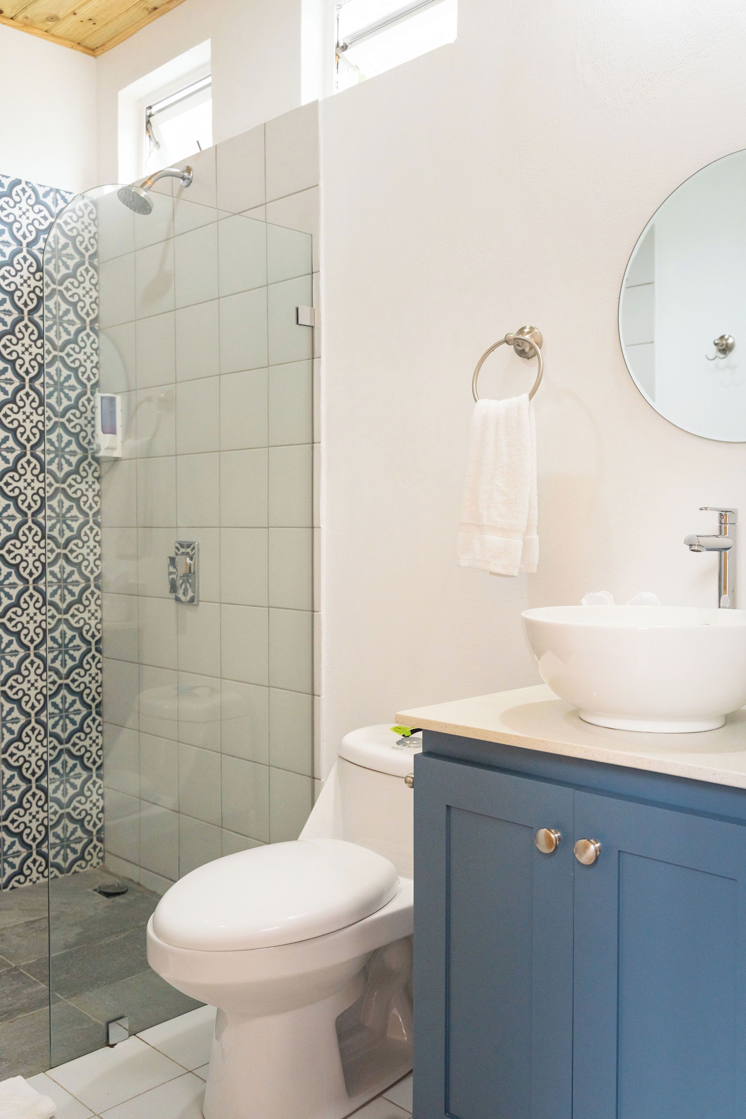 A bathroom with a shower, toilet, sink, and cabinet.