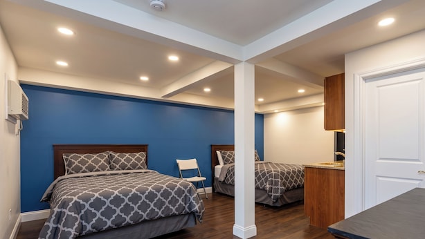 A bedroom with two beds, a wooden cabinet, and a white door.