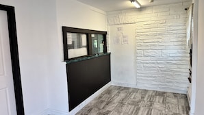 A hallway with a black partition, a stone-textured wall, and a tiled floor.