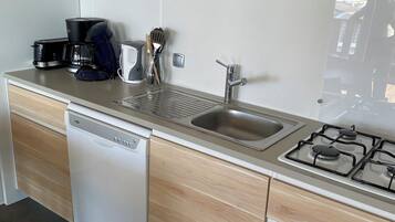 Una cucina moderna con mobili in legno, lavastoviglie, piano cottura e macchina da caffè.