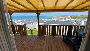 A wooden deck with a yellow canopy, overlooking a coastal town and the sea. - Mobile home sea view high up on the Opal Coast  (Le Portel)