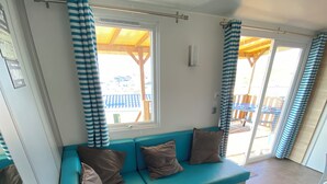 A modern living room with a blue sectional sofa, a wooden ceiling, and a view of an outdoor deck. - Mobile home sea view high up on the Opal Coast  (Le Portel)