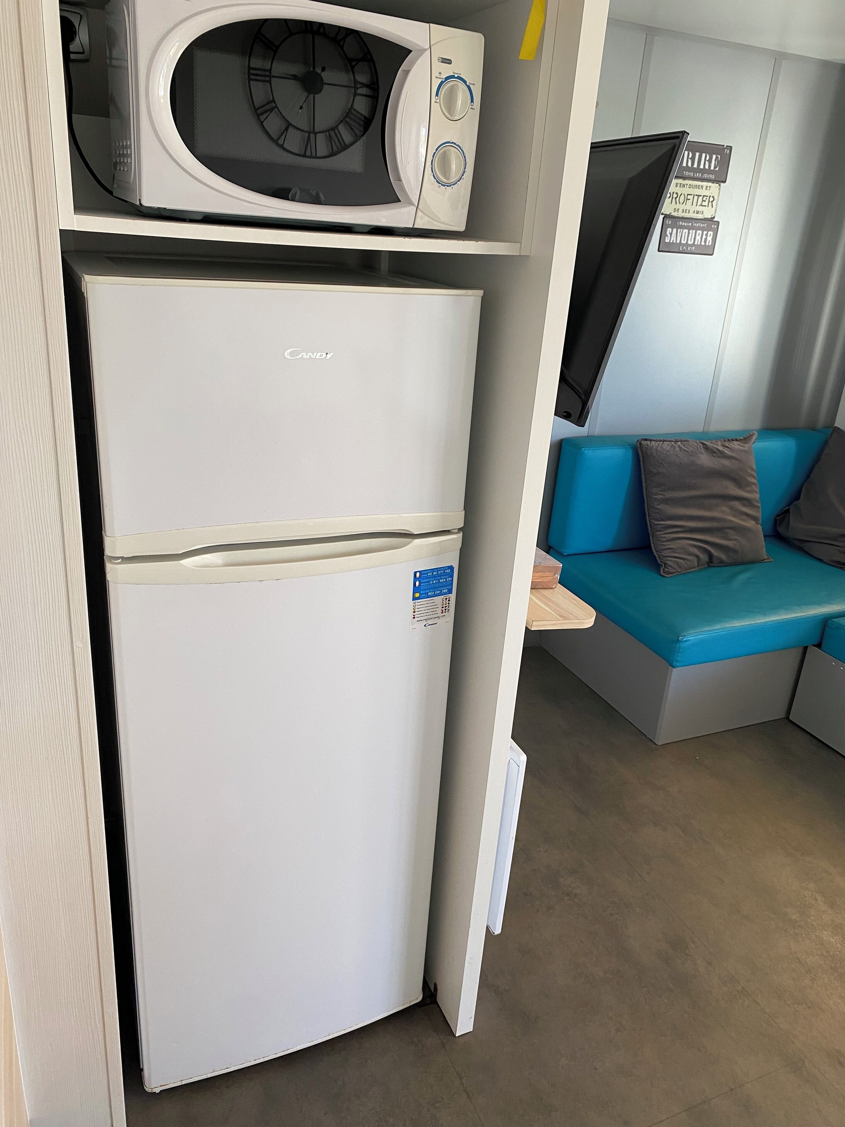 Una kitchenette compacta con un refrigerador blanco, un microondas y una pequeña encimera.