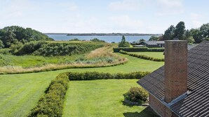 A residential property with a well-maintained lawn, a brick chimney, and a view of a lake with sailboats. - 3 bedroom nice home in Egernsund (Egernsund)