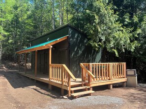 Escape to a cozy cabin surrounded by nature, with a covered porch and wooden deck.
