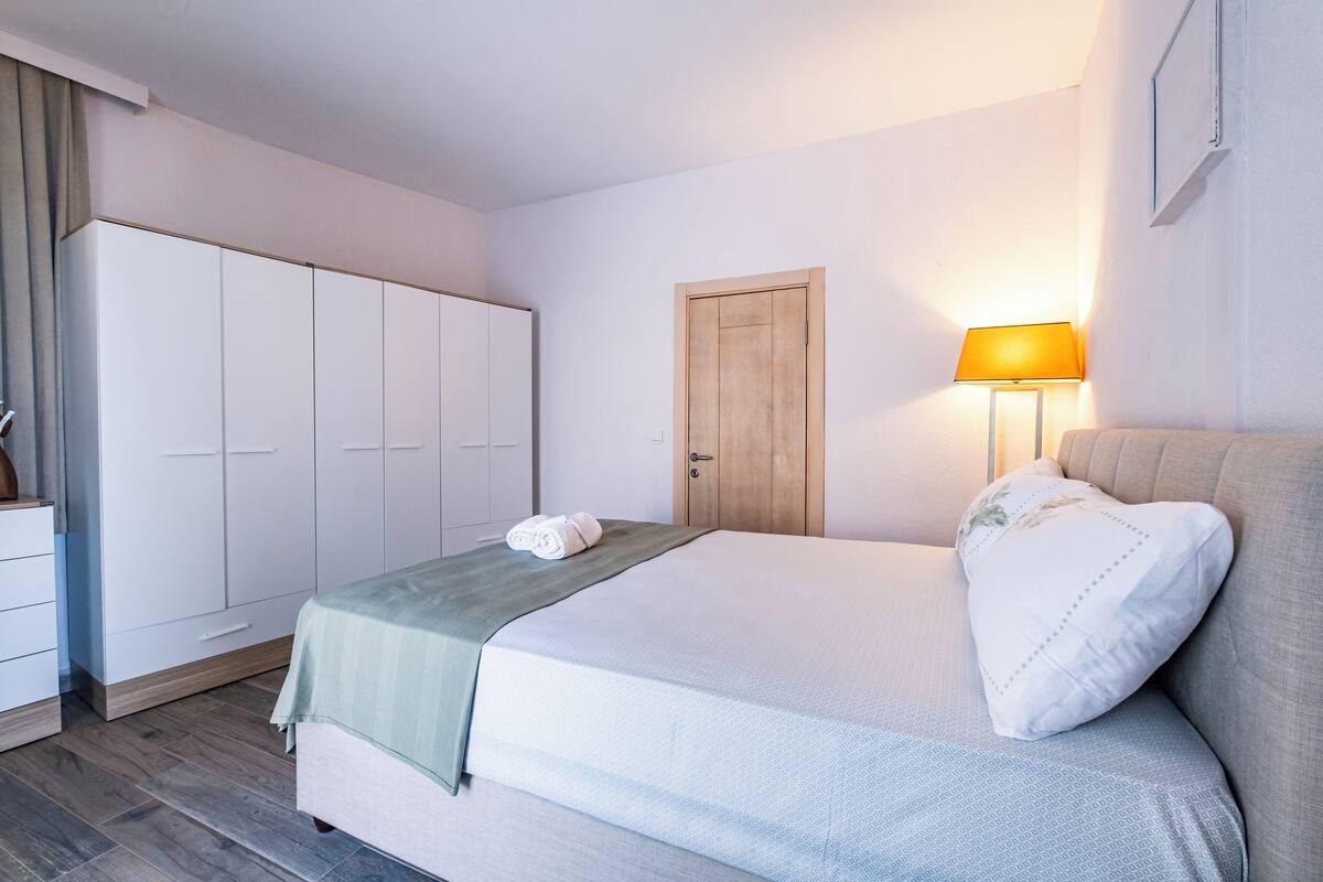 A bedroom with a bed, a wardrobe, a door, and a lamp.