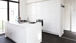 A modern kitchen with a central island, white cabinetry, and a large window providing natural light. - Modern Holiday Home 600 m From the sea (Breskens)