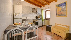 A kitchen with a dining table, chairs, a refrigerator, cabinets, and a wooden bench. - Casa Arx in Arco With 1 Bedrooms and 1 Bathrooms (Arco)