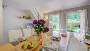 A dining area with a table set for two, a vase of flowers, and a bowl of apples. - Riva del Caolino in Ispra (Ispra)